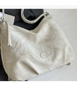 Détail de la texture marbre blanc cassé et du logo sur le sac fourre-tout en cuir