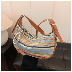 Detail of colorful woven straw bag with brown leather strap and pearl bow charm
