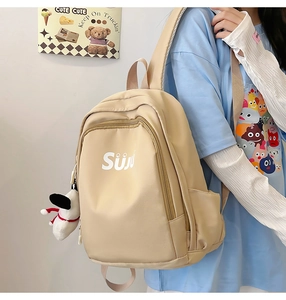 Detail of beige nylon backpack with Siju lettering and cute plush dog pendant