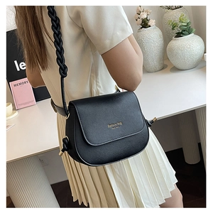 Detail of black pebbled leather saddle bag with woven strap and gold hardware