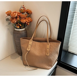 Detailed view of woven leather texture on a light brown tote bag for professional use