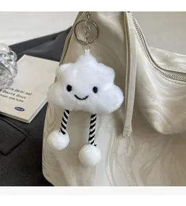 Gros plan d'un porte-clés nuage en peluche blanc avec visage souriant sur un sac