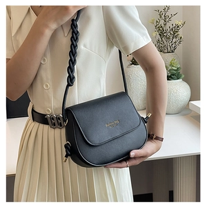 Detail of black saddle bag with gold lettering and unique thick woven braided shoulder strap