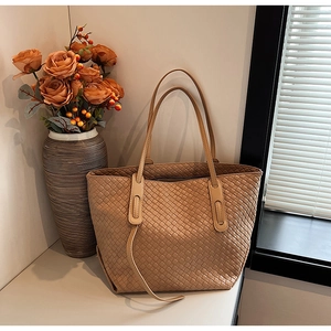 Detail of light brown woven tote bag showing the intricate classic braided texture