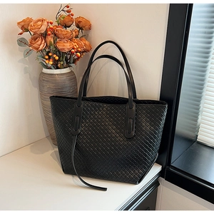 Macro detail of high-quality black woven leather texture on a spacious tote bag