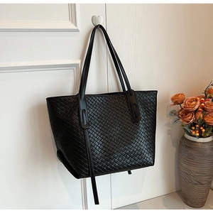 Detail of the woven leather texture and large capacity design of the black tote bag
