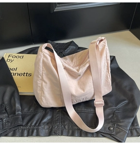 Pink nylon hobo bag featuring adjustable shoulder strap and front button pocket detail