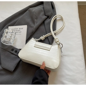 Detail of off-white crocodile embossed leather bag with knotted shoulder strap and flap