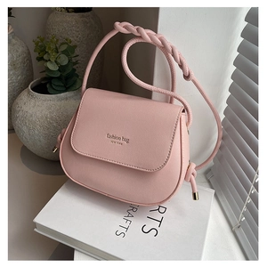 Detail of light pink crossbody bag with woven strap and fashion bag New York print