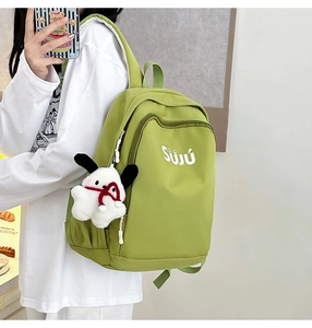 Detail of green nylon backpack featuring SUJU lettering and a plush dog charm pendant