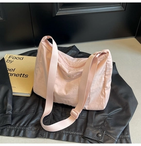 Light pink nylon crossbody bag with adjustable strap on a black leather jacket