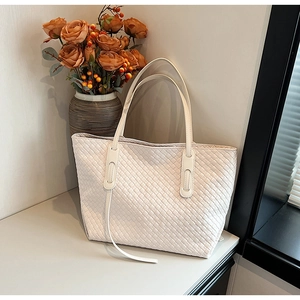 Close-up of white woven leather tote bag showing intricate texture and sturdy shoulder strap