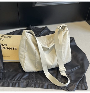 Detail of cream nylon crossbody bag featuring front pocket and wide adjustable strap