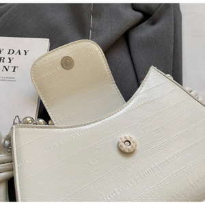 Detail of off-white pleated shoulder bag featuring magnetic closure and chunky silver beads