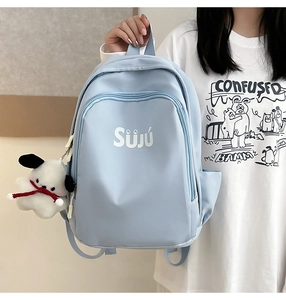 Detail of light blue casual backpack featuring a white logo and cute dog plush pendant
