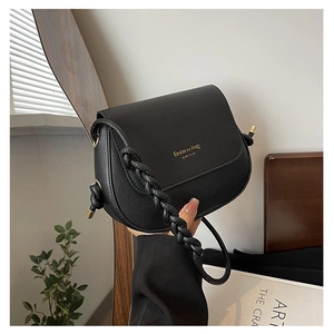 Detail of black pebbled saddle bag featuring a bold braided strap and gold fashion logo