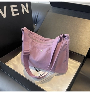 Detail of light purple nylon shoulder bag presented in a premium gift box setup