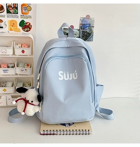 Detail of light blue nylon backpack with Süjú text, side pocket, and cute dog charm