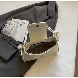 Detailed shot of white croc-embossed baguette bag with silver hardware on a blazer