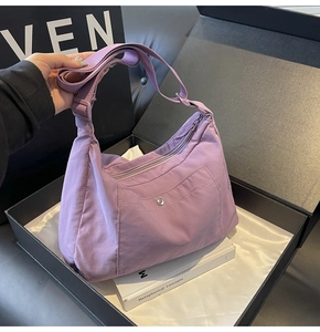 Detail of purple nylon crescent bag with snap front pocket and adjustable strap