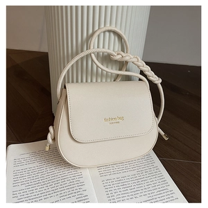 Detail of cream crossbody bag featuring a woven strap and New York fashion text