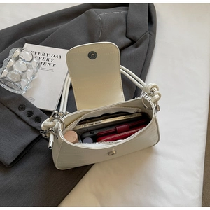 Detail showing inner capacity of white croc-embossed underarm bag with daily essentials
