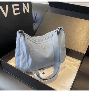Detail of light blue nylon crossbody bag with metal snap pocket in a gift box