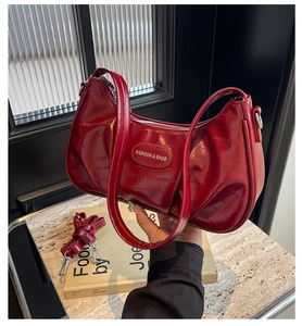 Détail du sac rouge verni brillant avec plaque en métal et bandoulière amovible