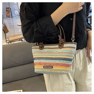 Colorful woven straw handbag with brown leather strap worn crossbody for summer vacation