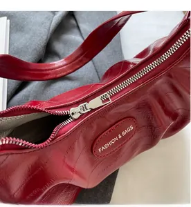 Détail d'un sac en cuir rouge brillant avec fermeture éclair argentée et logo de marque