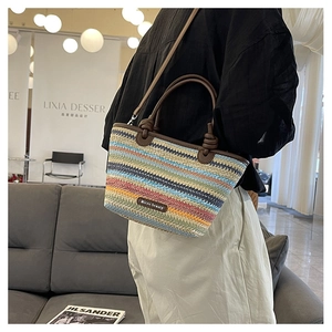 Close-up of rainbow striped woven bag with brown leather handles and knot design details