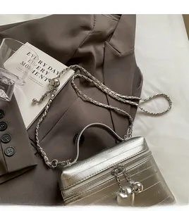 Vue détaillée du sac bandoulière argenté avec chaîne en métal et pendentif cœur chic