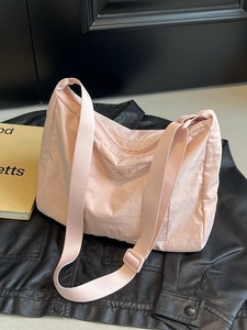 Pink lightweight nylon crossbody bag with adjustable strap on a stylish leather jacket