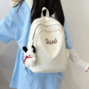 Creamy white PU leather backpack with SUJU print and plush dog charm on blue shirt