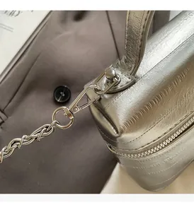 Détail d'un sac en cuir argenté métallisé avec texture verticale et chaîne polie