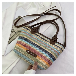 Detail view of colorful striped straw tote bag with brown leather handles and label