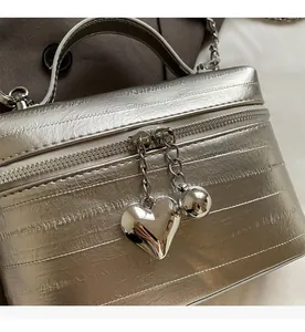 Détail d'un sac seau argenté avec pendentifs en forme de cœur et de boule en métal