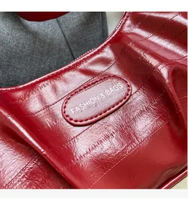 Détail d'un sac en cuir rouge brillant avec des plis chics et un logo ovale FASHION & BAGS