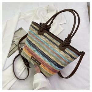 Detail of multi-color woven straw tote bag featuring brown leather knot handles and strap