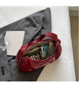 Détail de l'intérieur spacieux du sac à bandoulière en cuir verni rouge foncé et poches