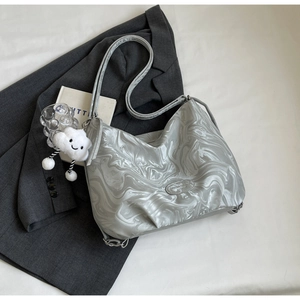 Détail du sac cabas argenté effet marbre avec charm nuage posé sur une veste grise
