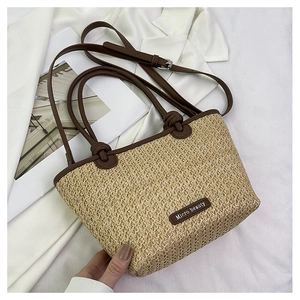 Detail of hand-woven straw tote bag featuring leather handles and Micro beauty logo