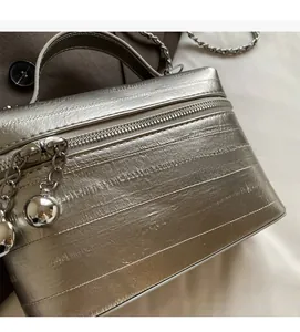 Détail du sac bandoulière argenté avec fermeture éclair à boule et chaîne métallique