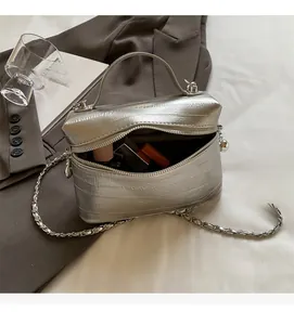 Gros plan d'un sac bandoulière argenté métallisé avec double fermeture éclair et chaîne