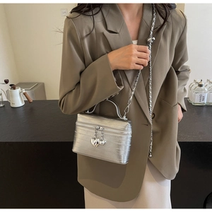 Sac boîte argenté chic avec texture métallique, chaîne et breloque cœur sur mannequin