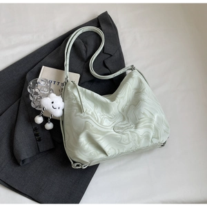 Détail du sac croissant vert clair avec texture marbrée et breloque nuage en peluche