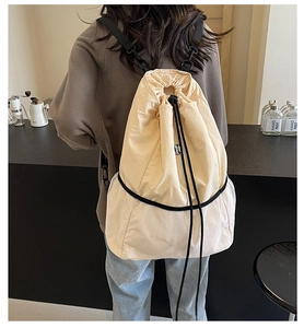 Detail of light beige nylon drawstring backpack featuring white mesh splicing on the bottom