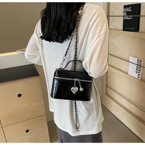 Détail du sac seau noir motif crocodile avec breloque cœur argentée et bandoulière