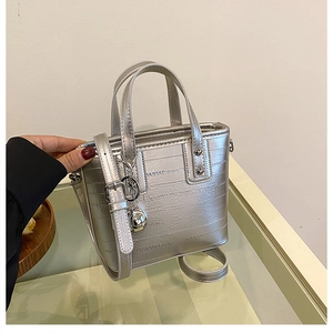 Détail du sac seau argenté à motif crocodile avec pendentif sphérique et poignée à main