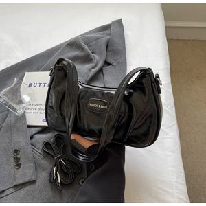 Gros plan du sac croissant en cuir verni noir avec logo et bandoulière amovible